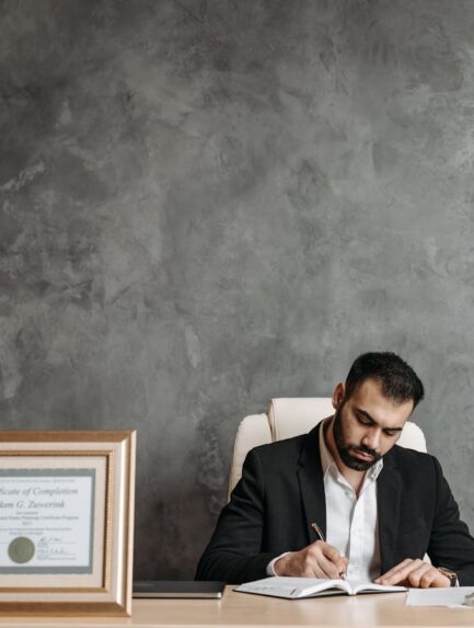 Photo by Pavel Danilyuk: https://www.pexels.com/photo/man-wearing-black-suit-writing-in-the-notebook-8112105/