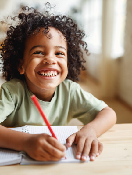 Smiling little boy doing homework while sitting at a desk
