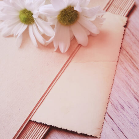 Empty page vintage book and summer flowers on wooden table. Love concept. Bouquet of chamomiles . Vintage effect