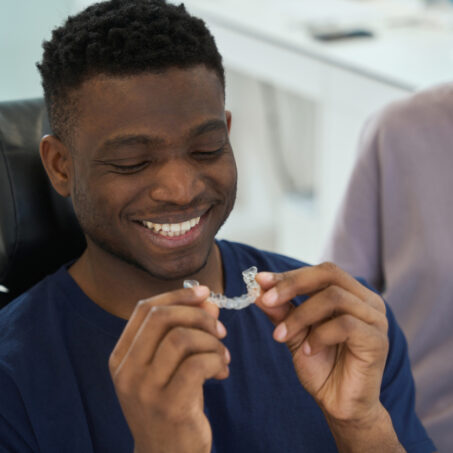 Young man wearing clear braces in order to get rid of malocclusion