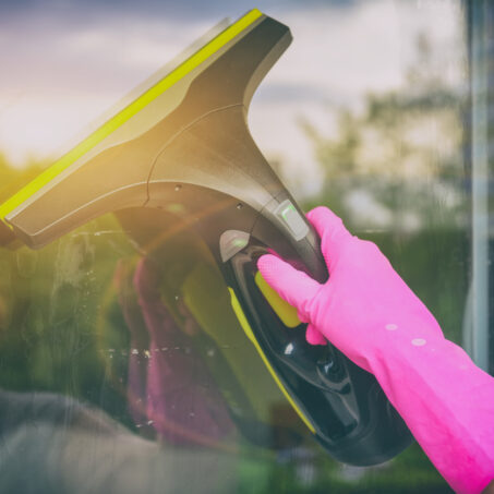 Cleaning windows with portable professional vacuum cleaner. Hand in protective glove