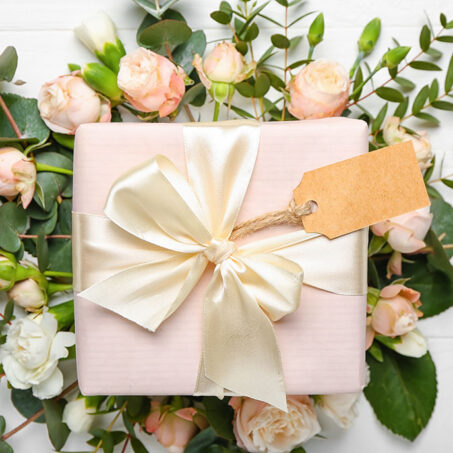 Beautiful flowers and gift on white wooden background